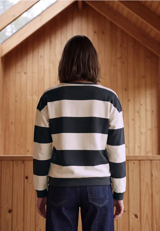 Persoon van achteren, gestreept shirt, houten ruimte, natuurlijke sfeer.
