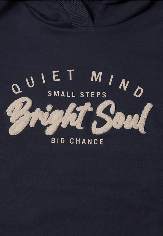 Dunkelblauer Pullover mit hellbeigeem Schriftzug 'Quiet Mind Small Steps Bright Soul Big Chance'.