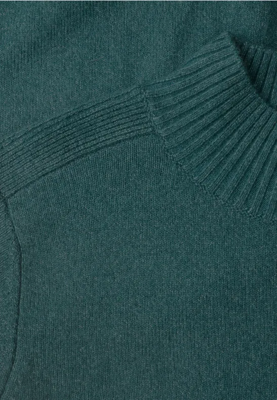 Pull en maille vert émeraude avec col montant et côtes fines.