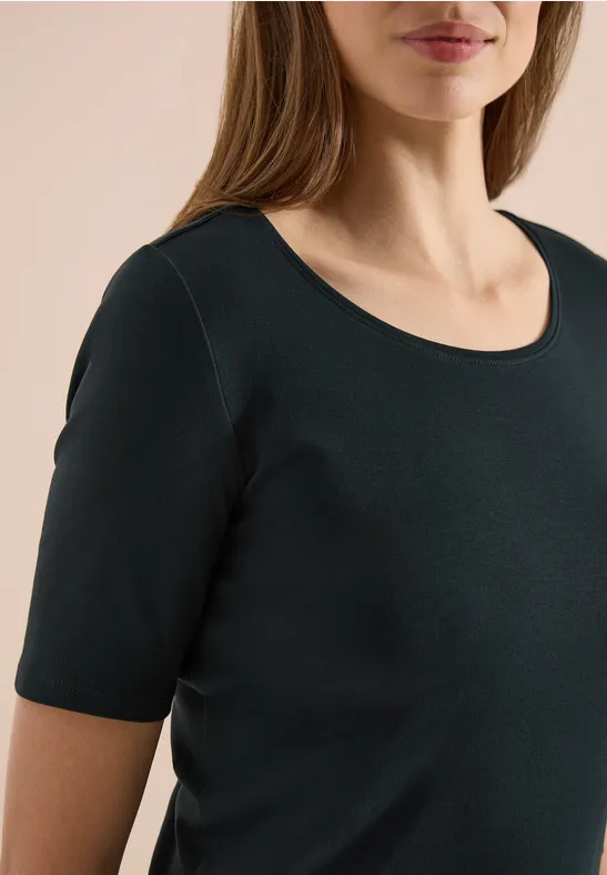 Frau trägt schlichtes schwarzes T-Shirt mit kurzen Ärmeln und Rundhalsausschnitt.