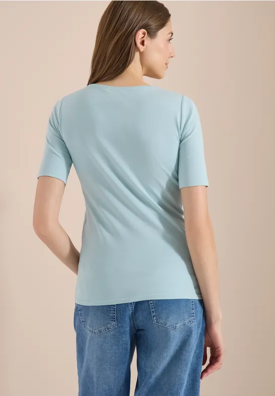 Eine Frau von hinten, hellblaues Shirt und Jeans.