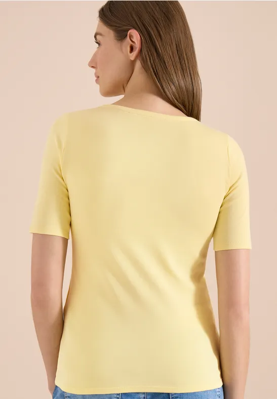 Eine Frau von hinten in einem gelben kurzärmligen Oberteil.