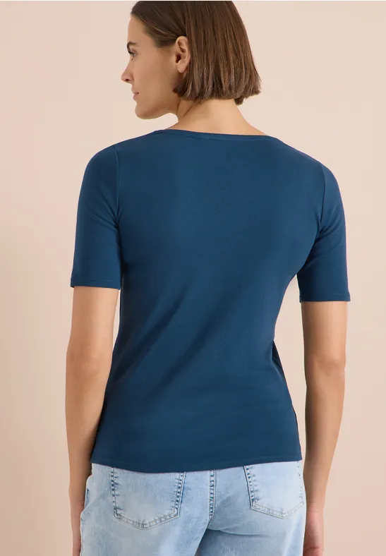 Rückenansicht einer Person mit dunkelblauem T-Shirt und hellblauen Jeans.