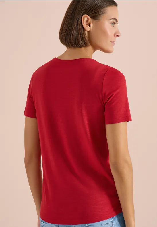 Frau von hinten in rotem T-Shirt, schlicht vor neutralem Hintergrund