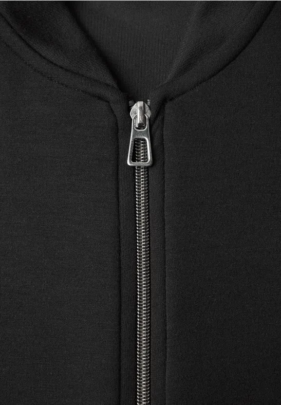 Gros plan d’une fermeture éclair métallique sur un sweat à capuche noir.