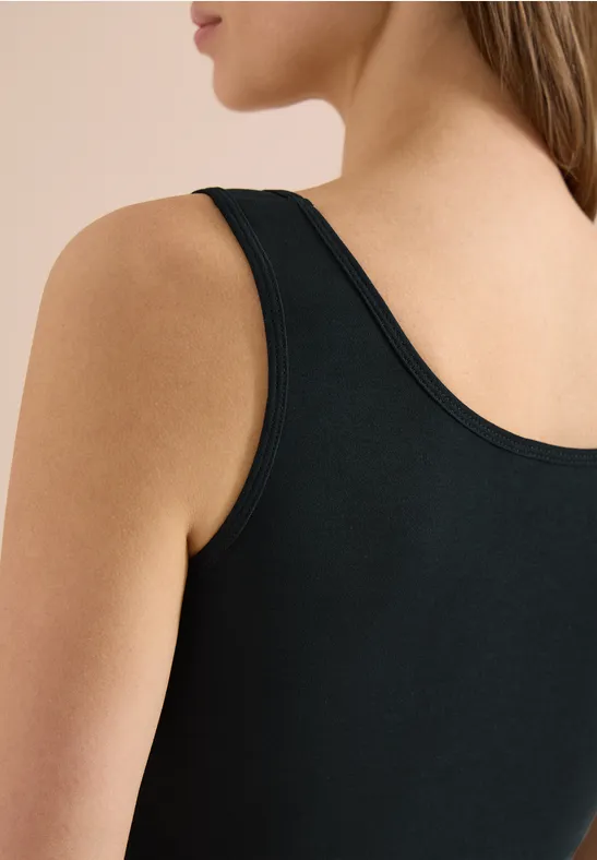 Nahaufnahme einer Frau im schwarzen ärmellosen Oberteil, Fokus auf Schulter und Rücken.