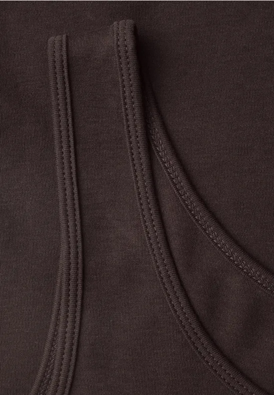 Nahaufnahme von zwei überlappenden, dunkelbraunen Baumwollshirts mit sichtbarer Naht