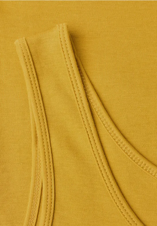 Detailaufnahme eines senfgelben Top-Stoffes mit Schulterträger