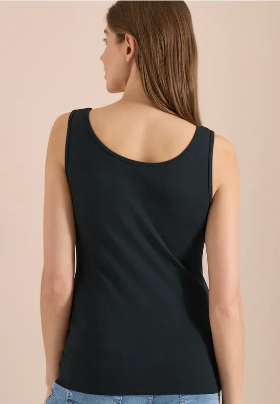 Frau von hinten in schlichtem schwarzen Top vor hellem Hintergrund.