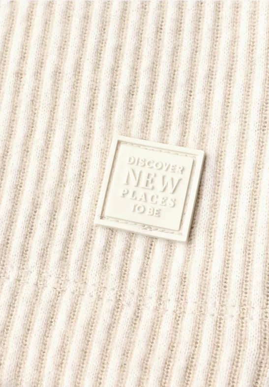 Beige ribstof met een vierkante patch met de tekst 'Discover New Places To Be'.