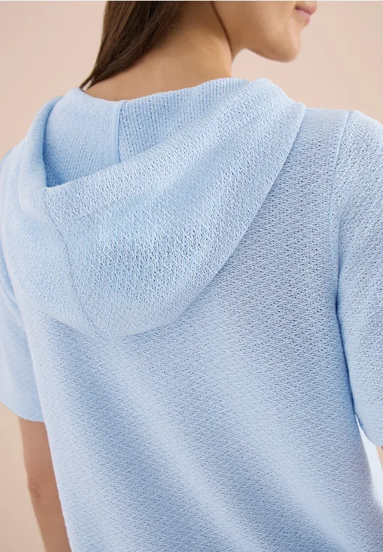 Persoon van achteren in een lichtblauwe, gestructureerde hoodie.