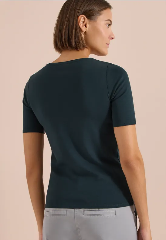 Frau von hinten, trägt ein dunkelgrünes Kurzarmshirt, kinnlanger Bob, neutraler Hintergrund.