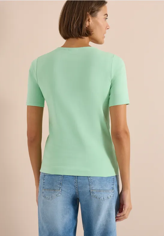 Frau von hinten in mintgrünem T-Shirt und blauen Jeans.