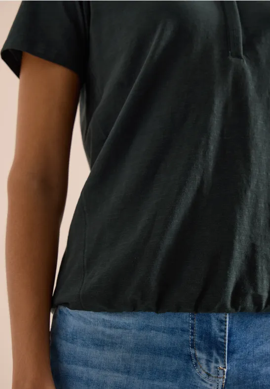 Een persoon draagt een zwart t-shirt en een blauwe spijkerbroek.