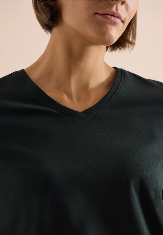 Nahaufnahme einer Person im dunklen V-Ausschnitt-Shirt, nur Kinn, Hals und Brust sichtbar.