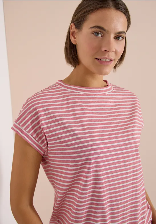 Eine Person trägt ein rosa-weiß gestreiftes T-Shirt vor hellem Hintergrund.