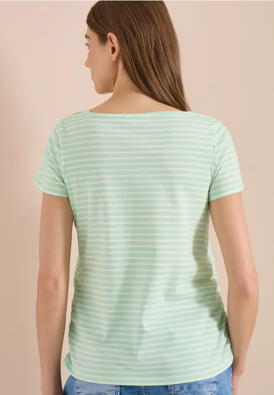 Femme de dos portant un t-shirt rayé vert menthe et blanc, cheveux bruns lâchés.