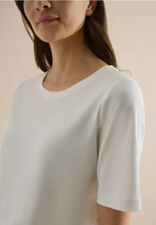Vrouw draagt eenvoudig wit T-shirt met korte mouwen en ronde hals.