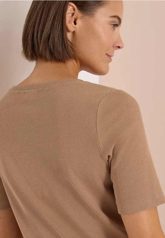 Rückenansicht einer Person mit kurzem Haar, die ein beigefarbenes T-Shirt trägt.
