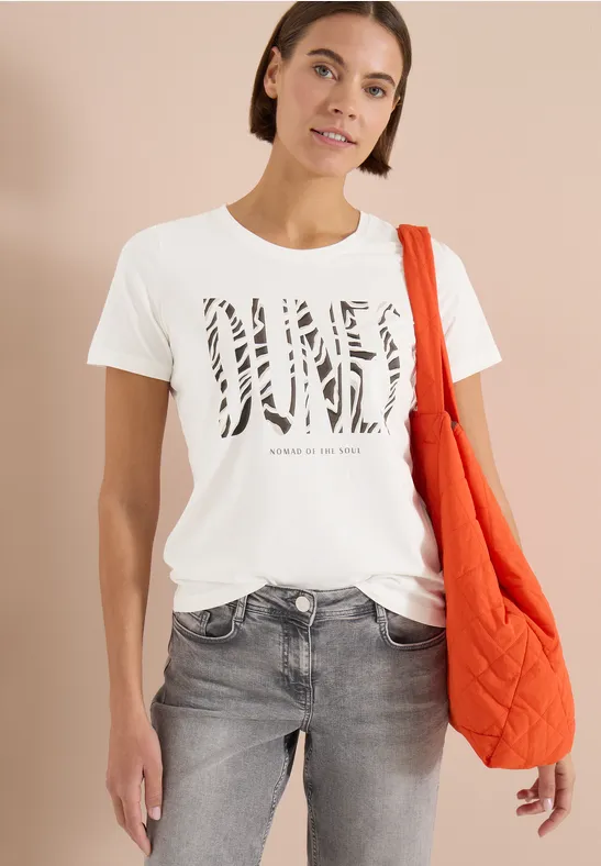 Frau trägt weißes T-Shirt mit Animal-Print-Schriftzug, graue Jeans und orangene Tasche.