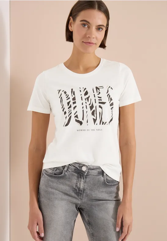 Frau trägt weißes T-Shirt mit Zebra-Print-Schriftzug und grauen Jeans.