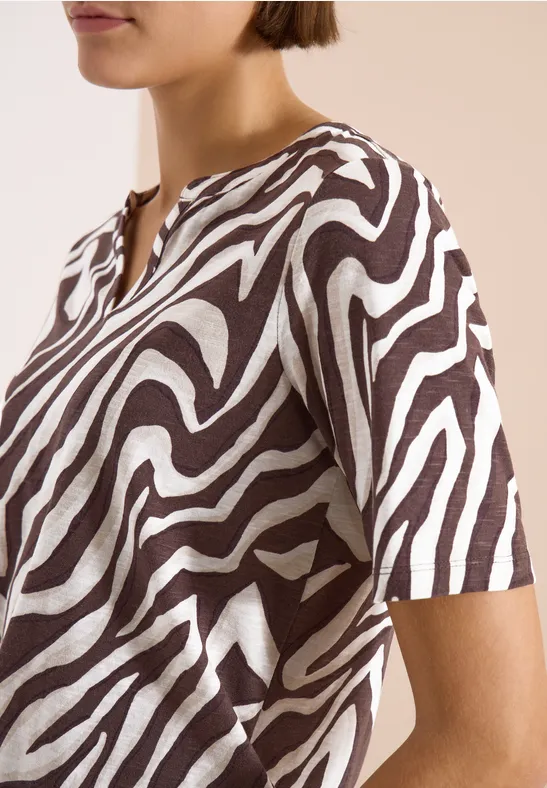 Een vrouw draagt een T-shirt met korte mouwen en bruin-witte zebraprint.