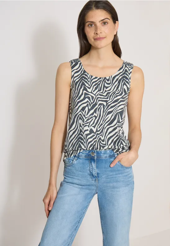 Personne porte un top sans manches à imprimé zèbre et un jean bleu clair.