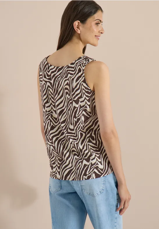Femme de dos vêtue d'un top sans manches motif zèbre et d'un jean clair.