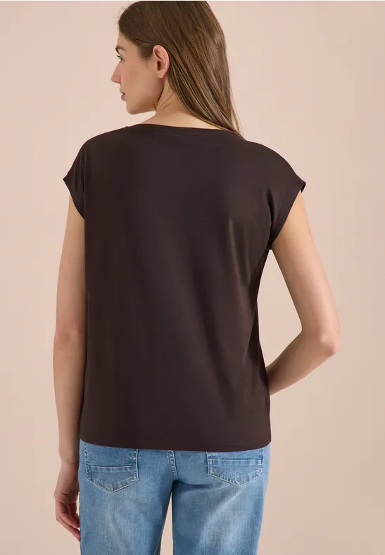 Vrouw van achteren in donker bruin t-shirt en blauwe spijkerbroek voor lichte achtergrond