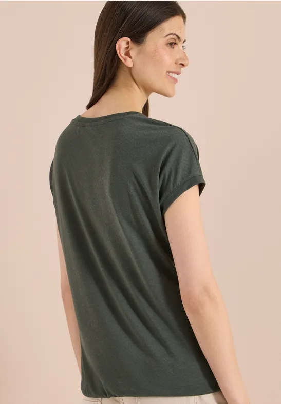 Vrouw van achteren in donker groen T-shirt voor een neutrale achtergrond.