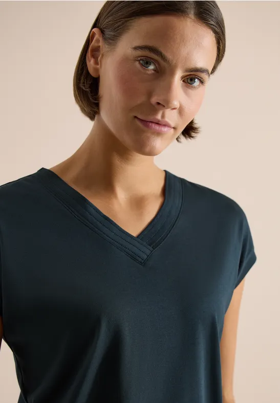 Person trägt dunkelblaues V-Ausschnitt-T-Shirt mit kurzen Ärmeln.