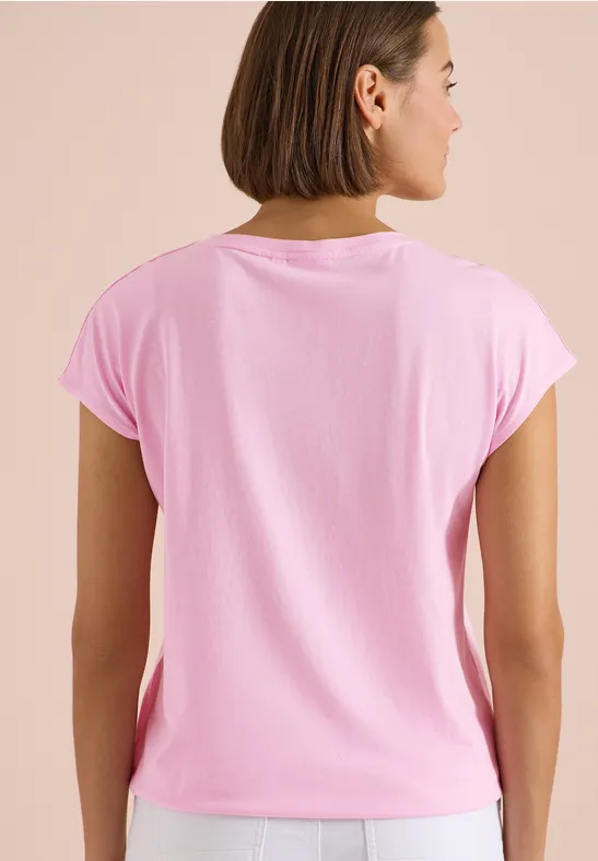 Achteraanzicht van een vrouw met halflang haar die een lichtroze, kort T-shirt draagt.