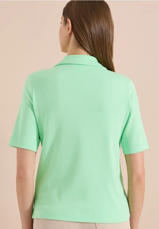 Rückenansicht einer Person in einem hellgrünen, kurzärmeligen Poloshirt.