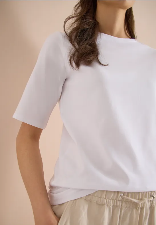 Vrouw met een wit T-shirt en comfortabele lichte broek voor een neutrale achtergrond