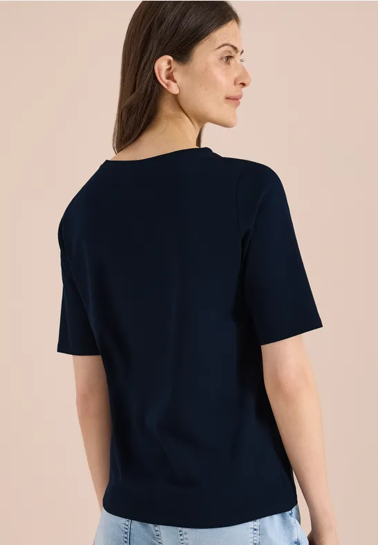 Achteraanzicht van een persoon in een donkerblauw T-shirt met korte mouwen tegen neutrale achtergrond.