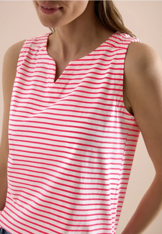 Frau trägt ärmelloses Top mit roten und weißen Streifen.