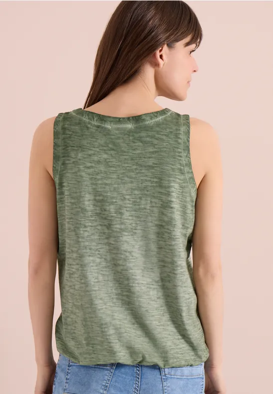 Een vrouw van achteren in een groen mouwloos shirt met licht gerimpelde zoom.