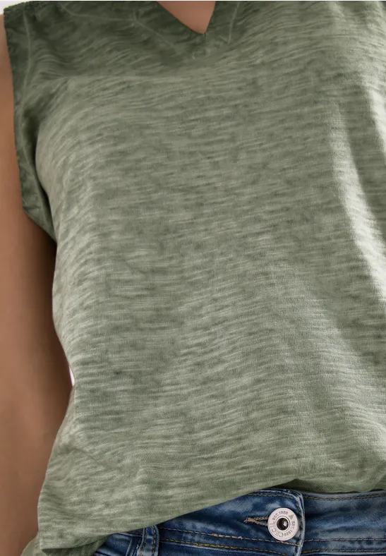 Close-up van een torso in een groen T-shirt en blauwe jeans.