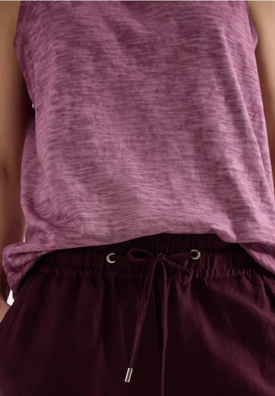 Casual outfit: paarse tanktop en bordeauxroze broek met trekkoord.