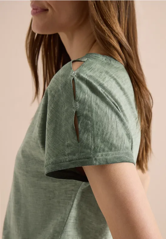 Seitlicher Blick auf eine Frau in einem grünen T-Shirt mit zwei Schulter-Schlitzen.