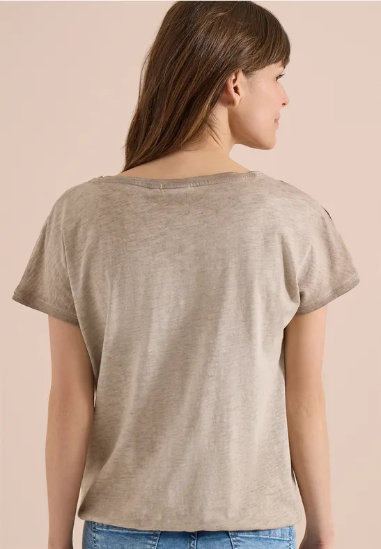 Eine Frau von hinten in beige T-Shirt mit kurzen Ärmeln und braunen Haaren.