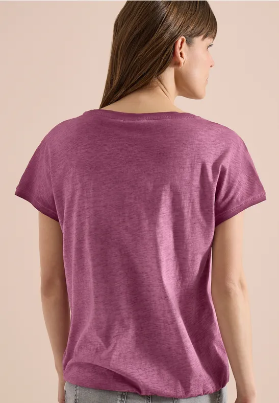 Rückenansicht einer jungen Frau mit langem braunem Haar, die ein kurzärmeliges lila T-Shirt trägt.