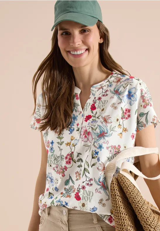 Vrouw in witte bloemenblouse met ruches, houdt een strozak vast.