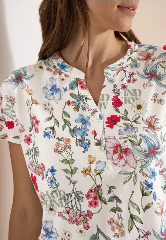 Wit shirt met korte mouwen, kleurrijke bloemenprint en een kleine inkeping bij de ronde hals.