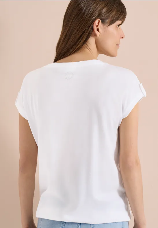 Rückansicht einer Frau in schlichtem weißen T-Shirt vor neutralem Hintergrund.