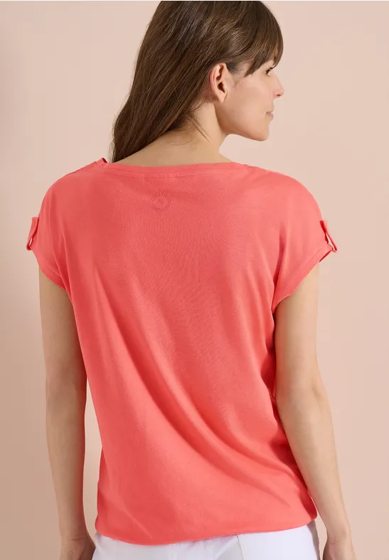 Rückenansicht eines korallenroten, kurzärmeligen Oberteils an einer Frau.