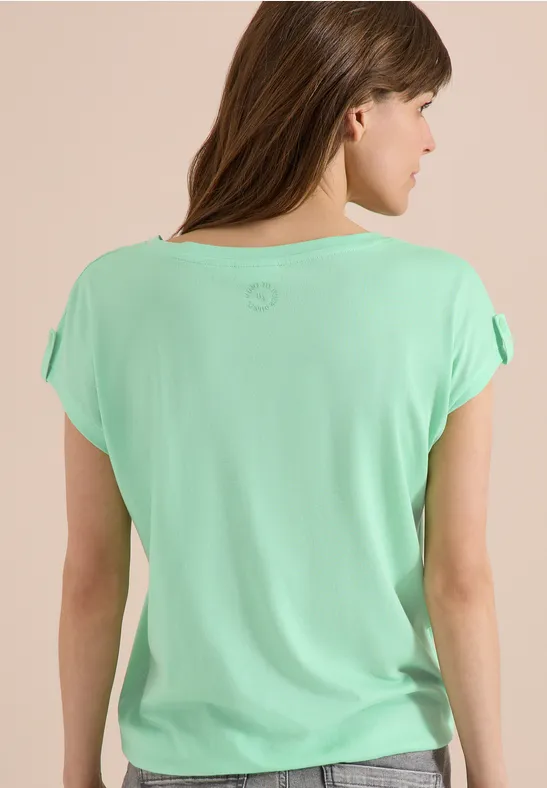 Vrouw van achteren in mintgroen T-shirt met losse korte mouwen, lang bruin haar.