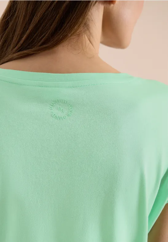 Close-up van de rug van een vrouw in een muntgroen t-shirt voor neutrale achtergrond.