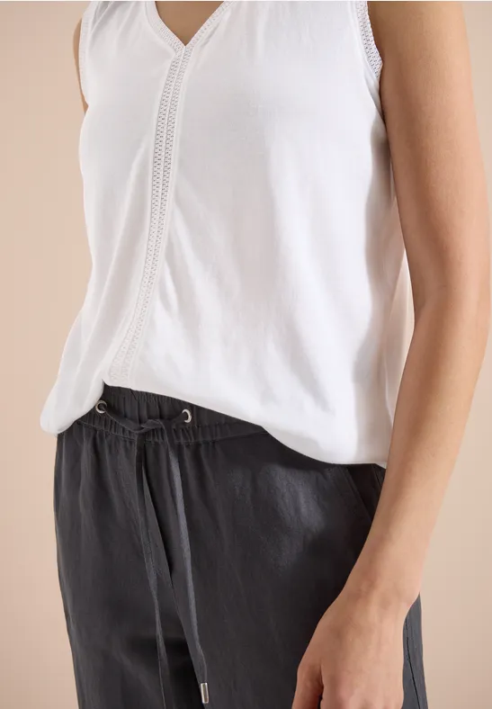 Witte mouwloze top en zwarte broek met koord, casual stijl.