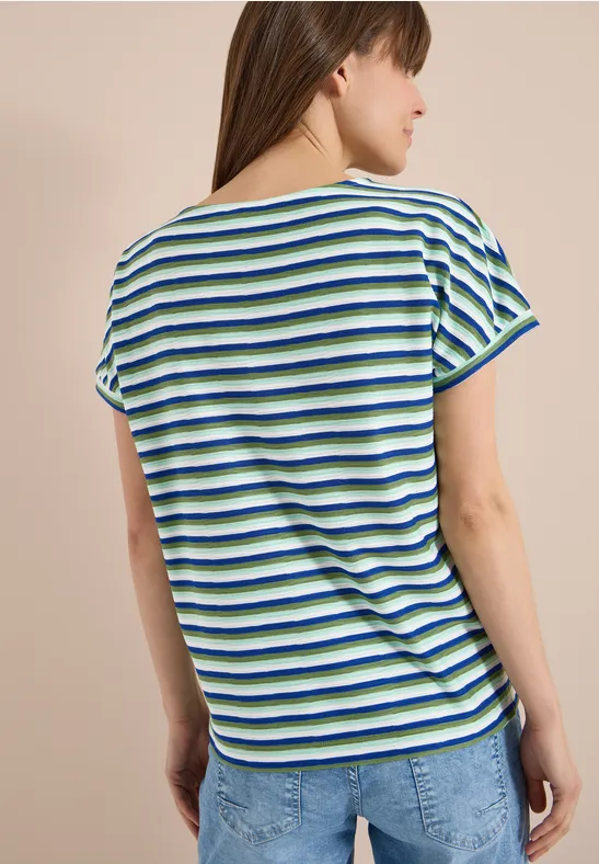 Vrouw met rug naar camera draagt gestreept T-shirt met korte mouwen en spijkerbroek.